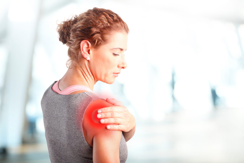 Portrait of sporty woman putting her hand on red spots on while has sport injury in her shoulder.
